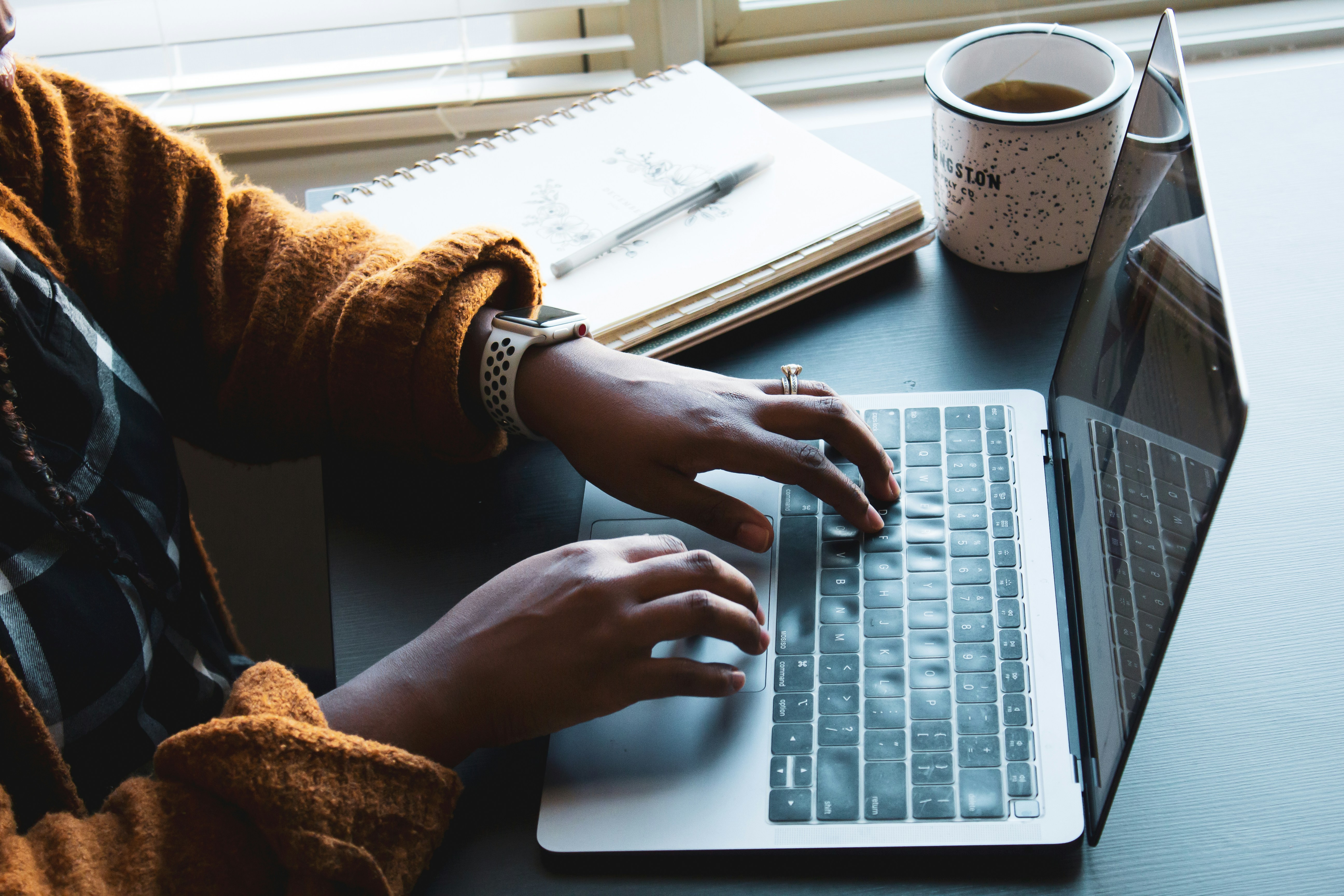 Image shows a woman's hands typing on a laptop